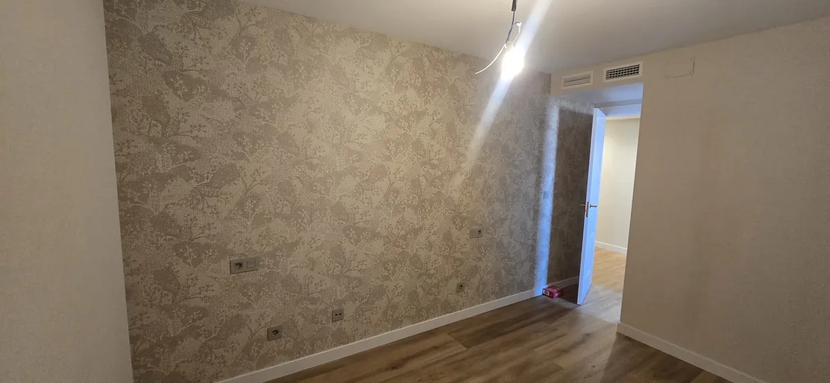 Dormitorio con papel pintado texturado en tonos neutros junto a pasillo