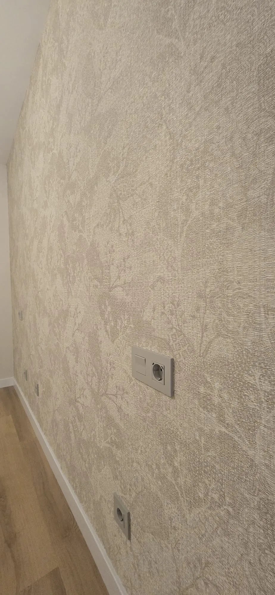 Detalle de papel pintado texturado en tonos neutros bajo techo abuhardillado