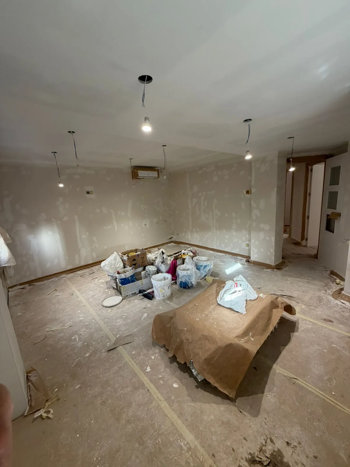Habitación con paredes masilladas antes de pintar, aire acondicionado y luces sin instalar