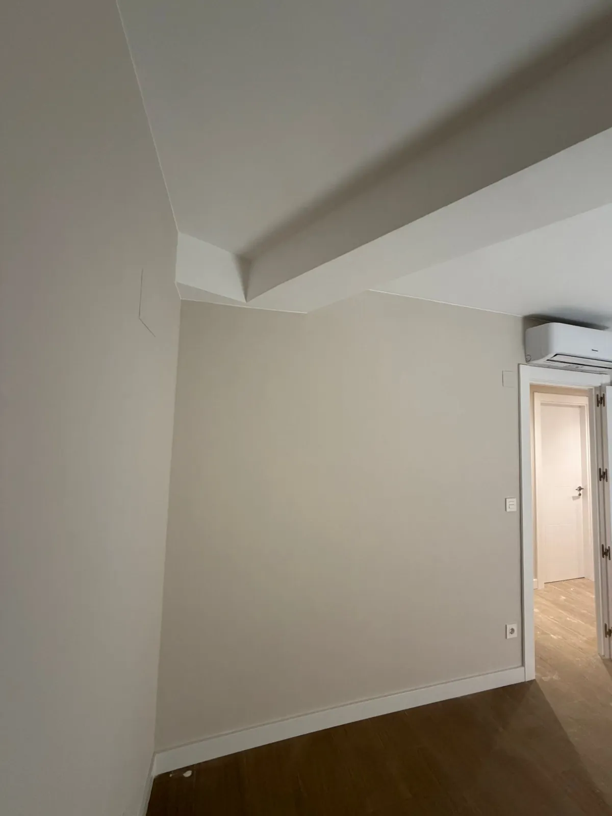 Habitación con techo abuhardillado, pared en tono cálido y aire acondicionado