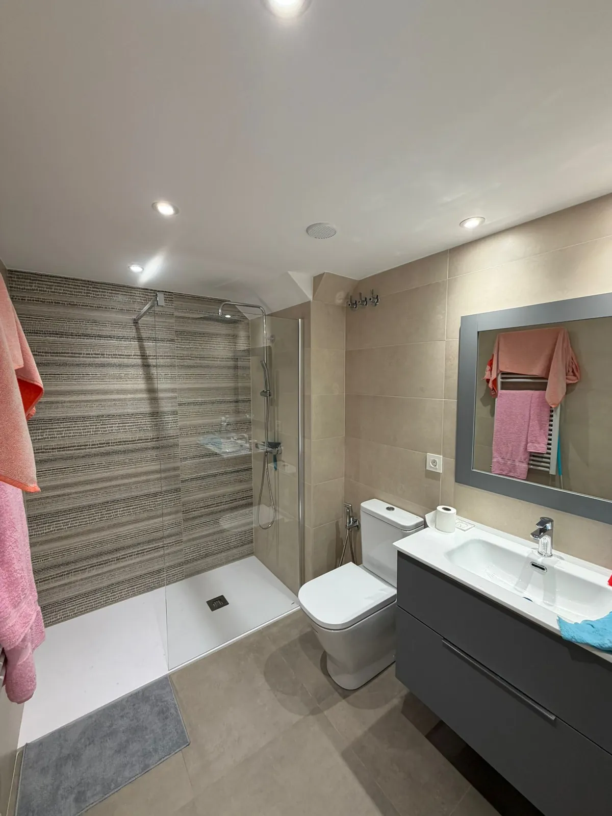 Baño moderno terminado con mampara de cristal, ducha de lluvia y azulejo texturado