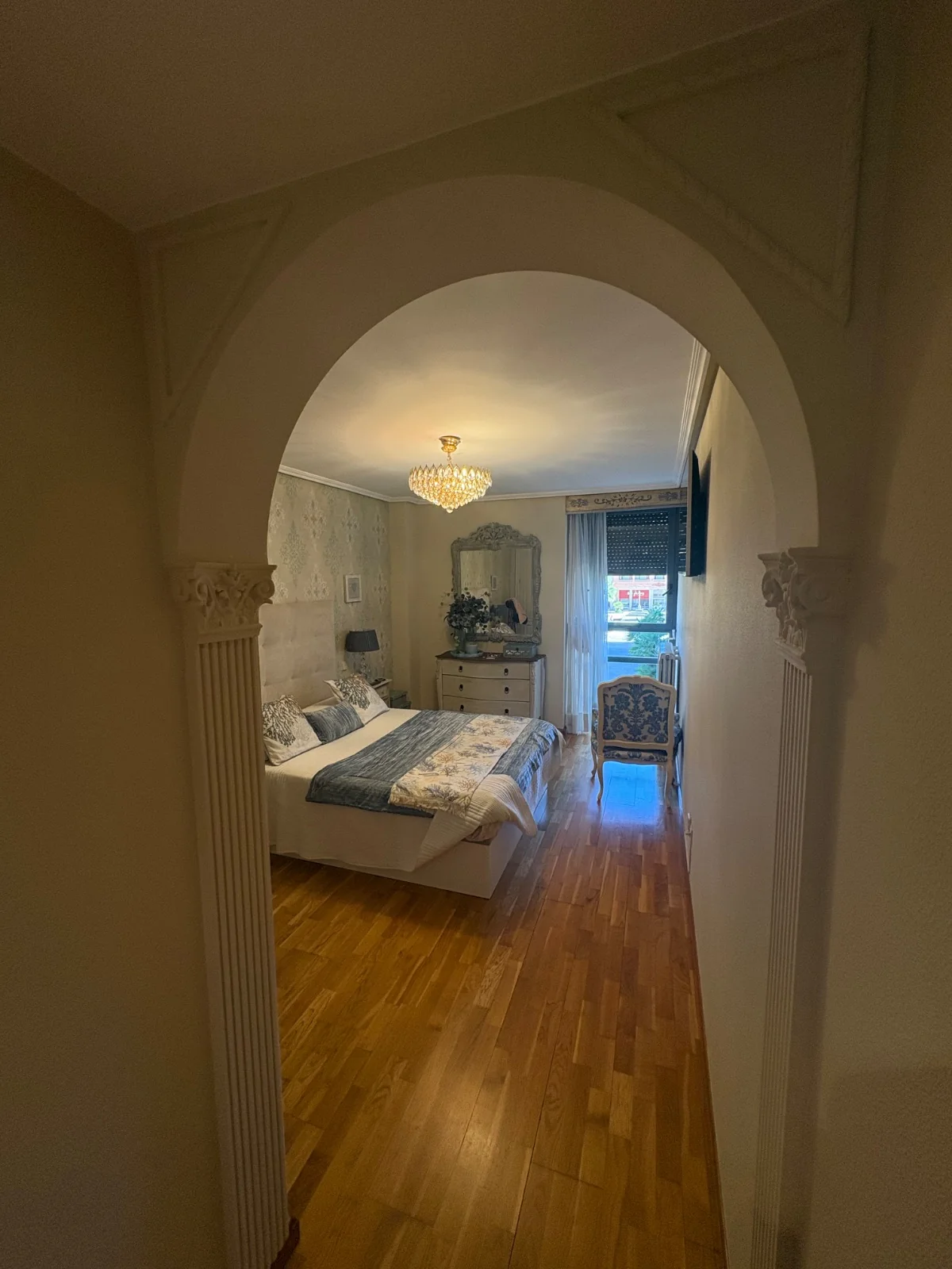 Dormitorio empapelado visto desde el arco del pasillo