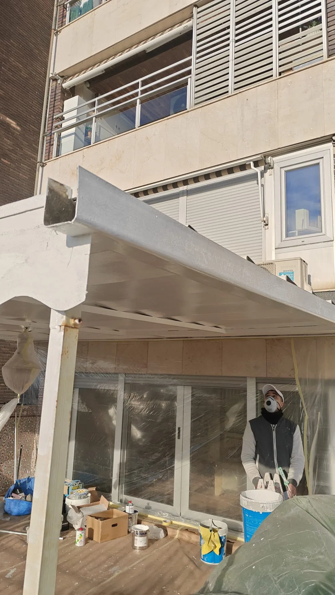Pintor esmaltando la estructura metálica de una pérgola con esmalte de poliuretano